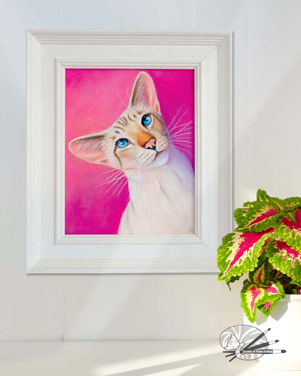 Framed painting of a siamese cat with a pink background in a white frame on a wall.